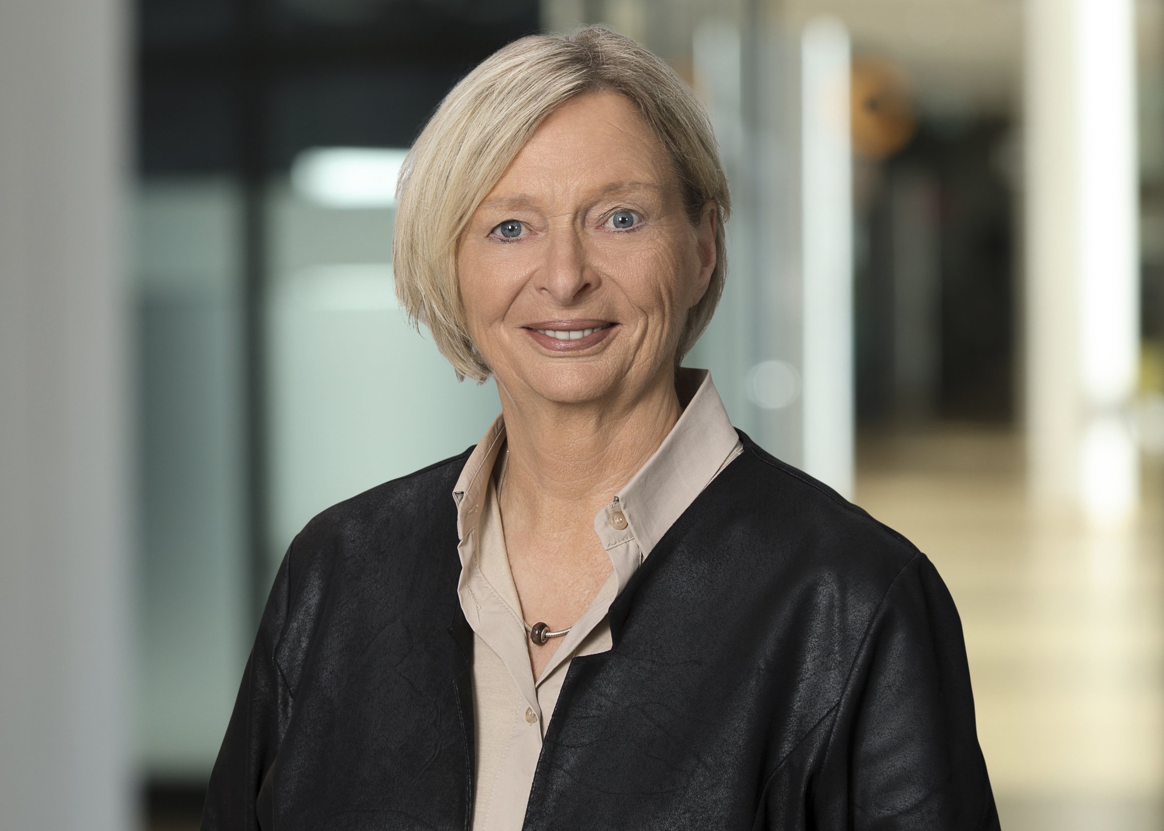 Portrait ältere Frau mit modischen Bob und blonden Haar in schwarzem Blazer mit beigefarbener Bluse