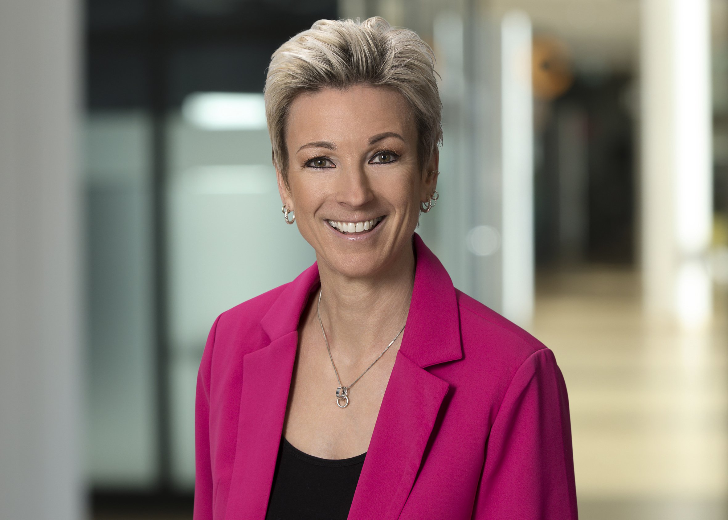 Portrait Frau mit blonden kurzen Haaren im pinkfarbenen Blazer